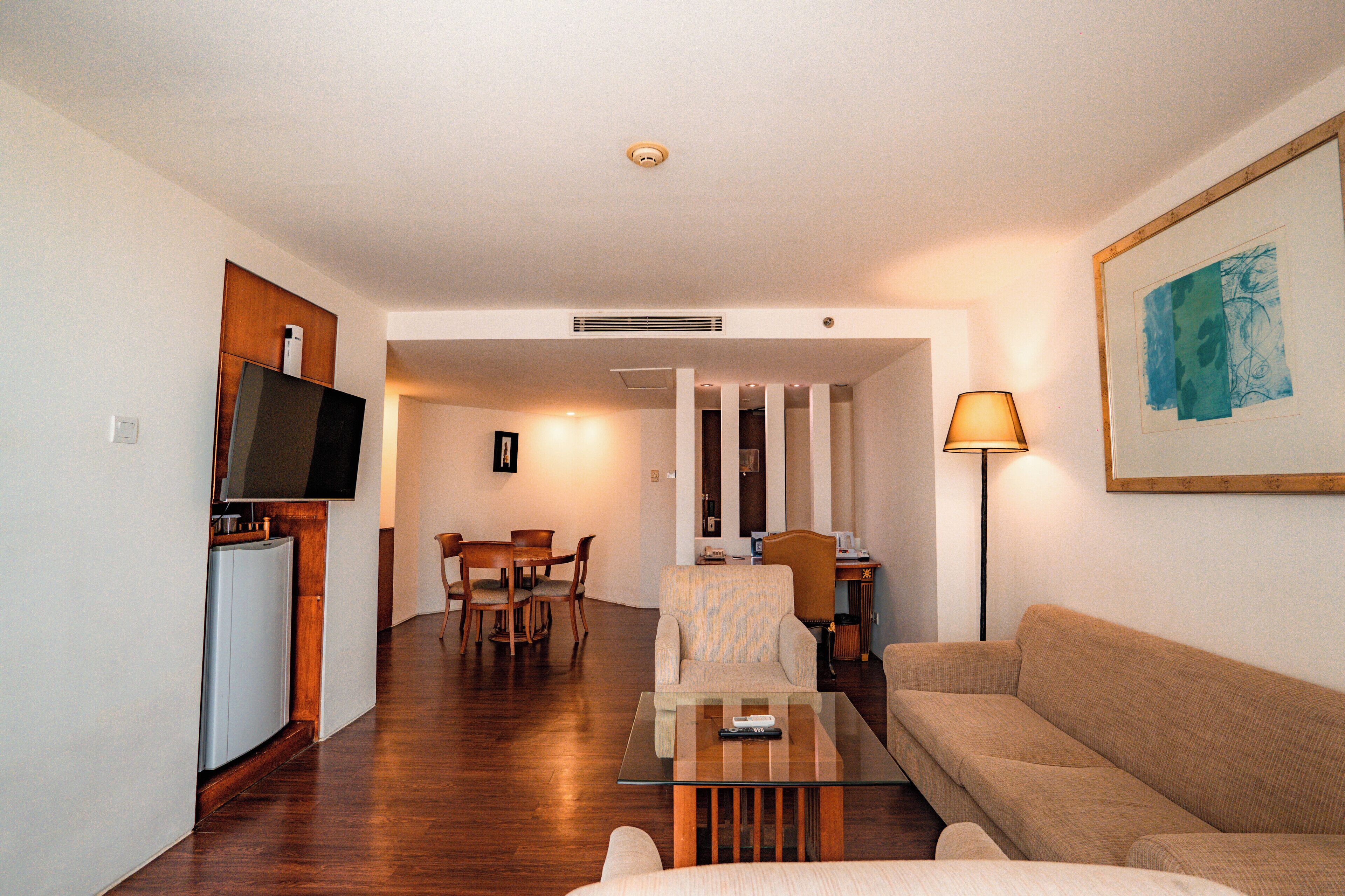 Una sala de estar con sofá, mesa de centro, televisor y comedor con sillas y mesa.