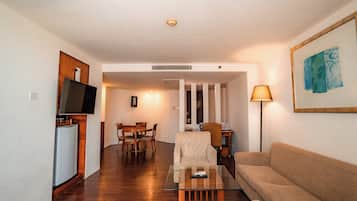 Una sala de estar con sofá, mesa de centro, televisor y comedor con sillas y mesa.