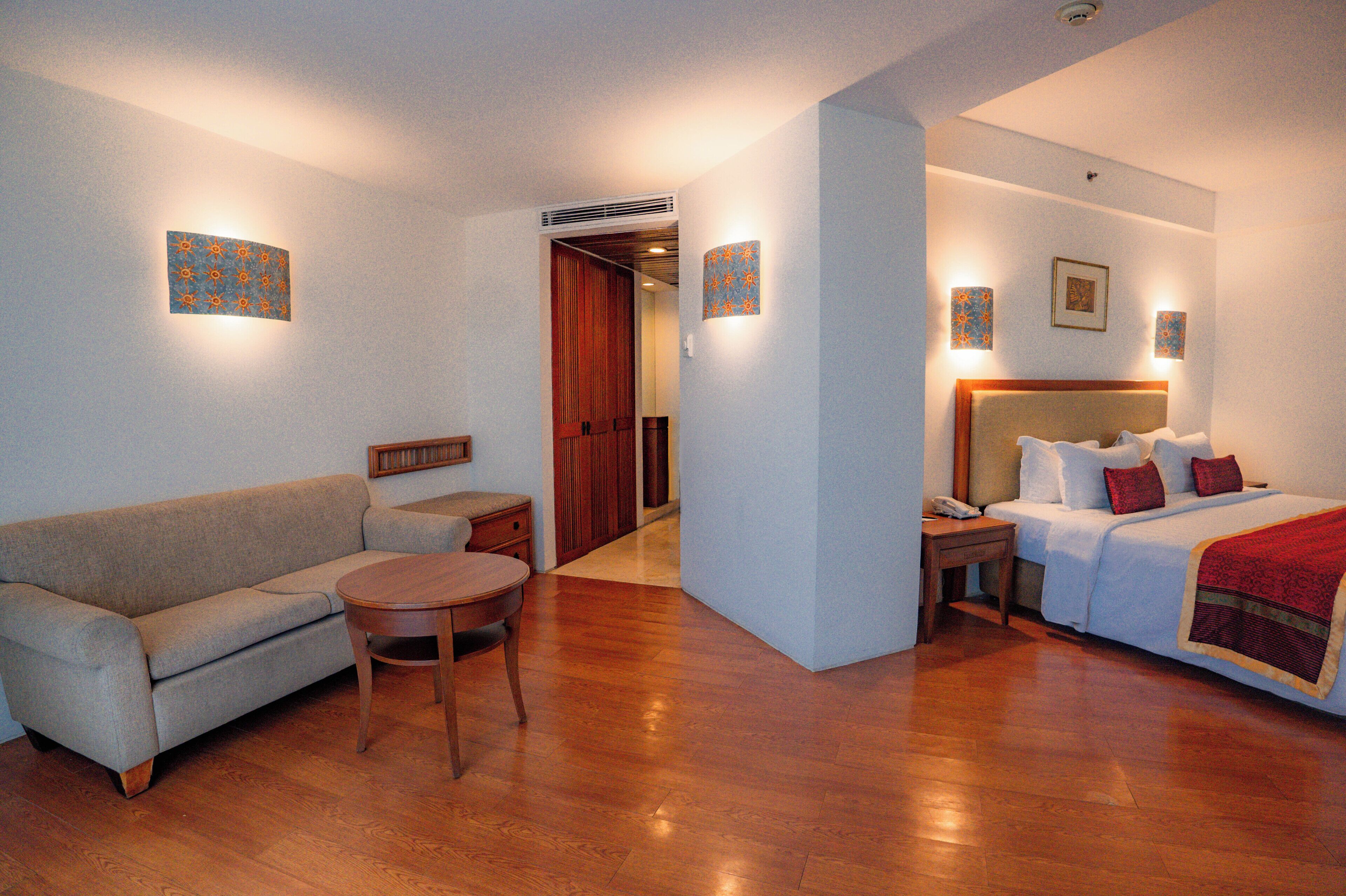 Ein Hotelzimmer mit Bett, einer Couch, einem kleinen Tisch und einem Nachttisch.