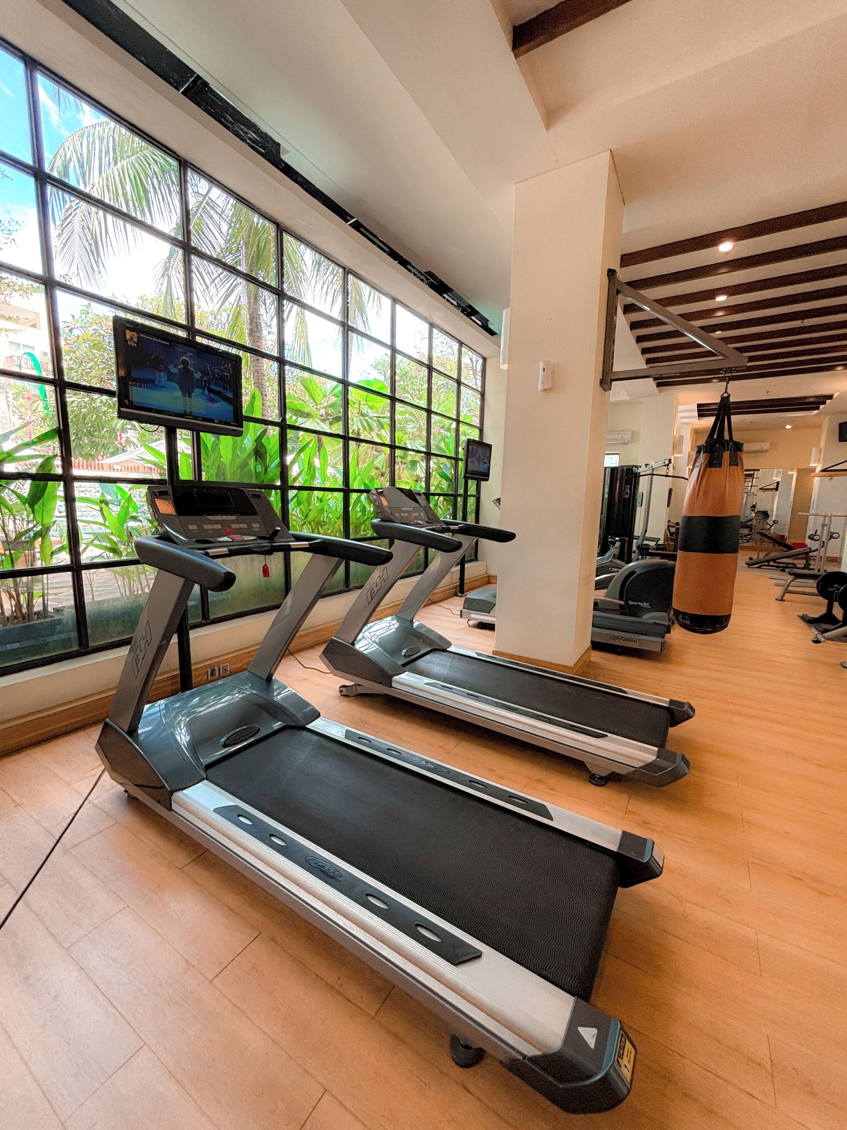 A gym with treadmills, a punching bag, and a TV screen.