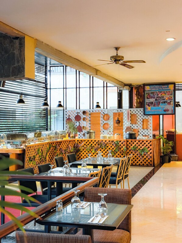 A restaurant with a modern interior, featuring a long counter, multiple dining tables, and a variety of seating options including booths and chairs. - Kuta Paradiso Hotel (Kuta)