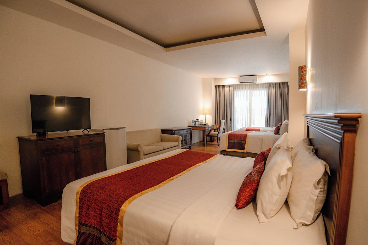Una habitación de hotel con una cama grande, un escritorio, una televisión y una ventana con cortinas.