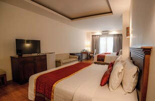 Una habitación de hotel con una cama grande, un escritorio, una televisión y una ventana con cortinas.