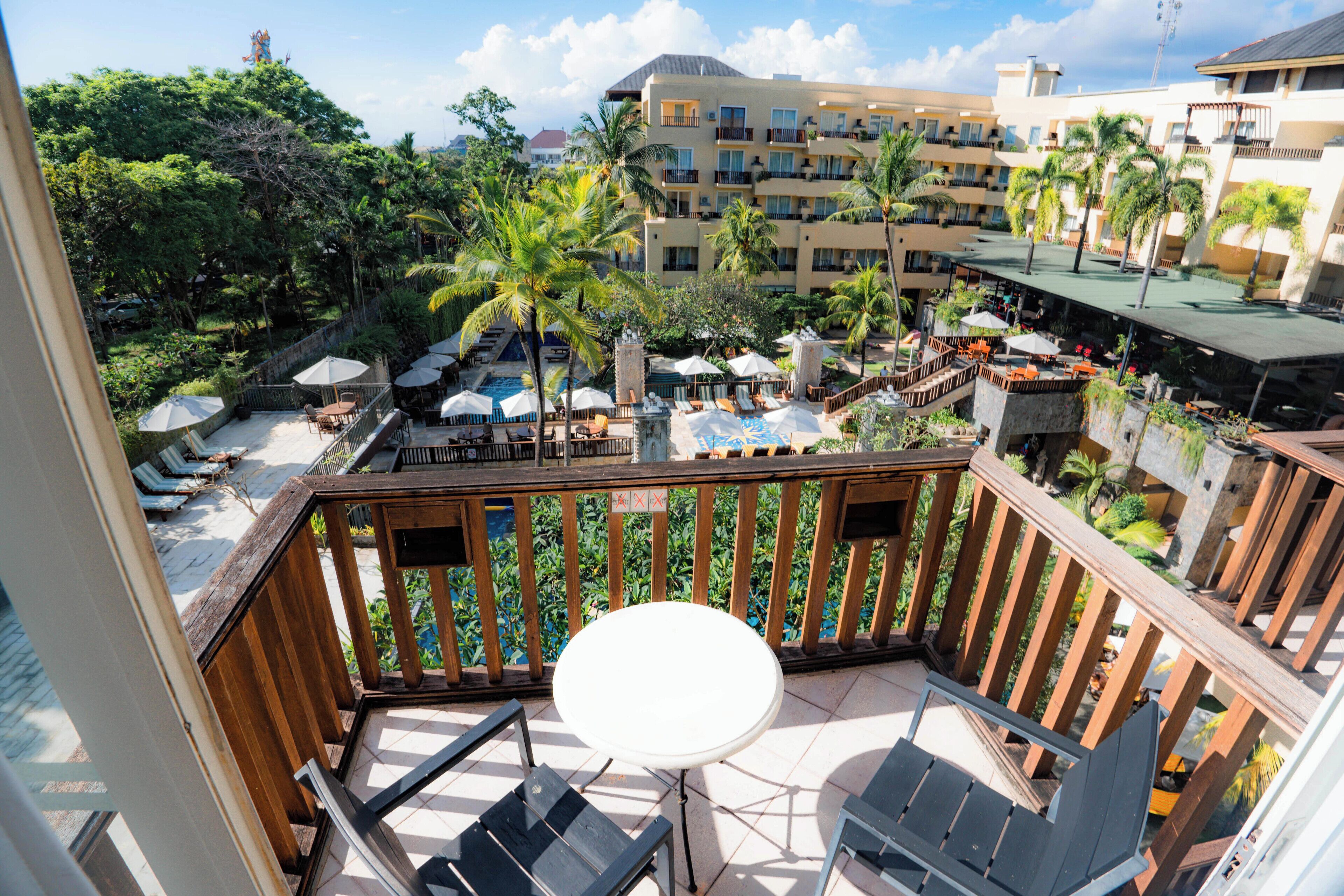 Um resort com área de piscina, assentos externos e vista para os edifícios ao redor.
