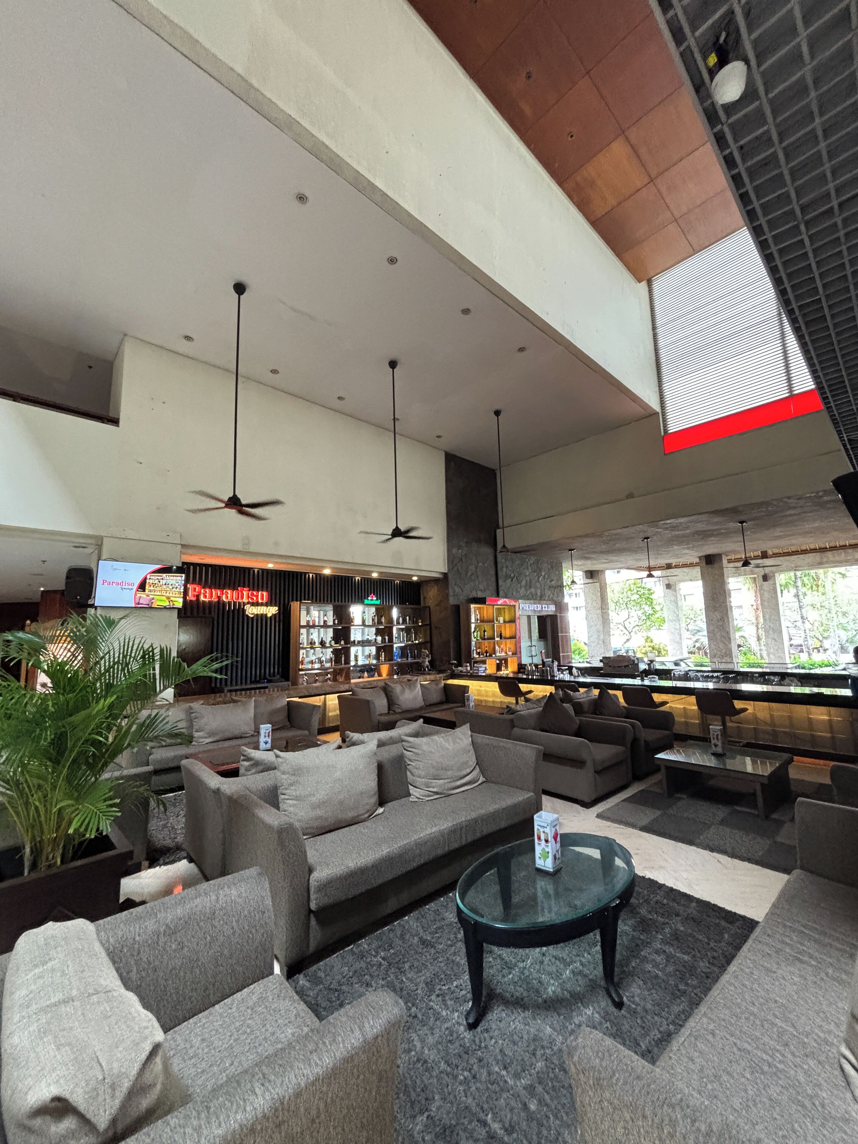 A spacious lobby with multiple seating areas, a bar, and ceiling fans.