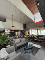 A spacious lobby with multiple seating areas, a bar, and ceiling fans.