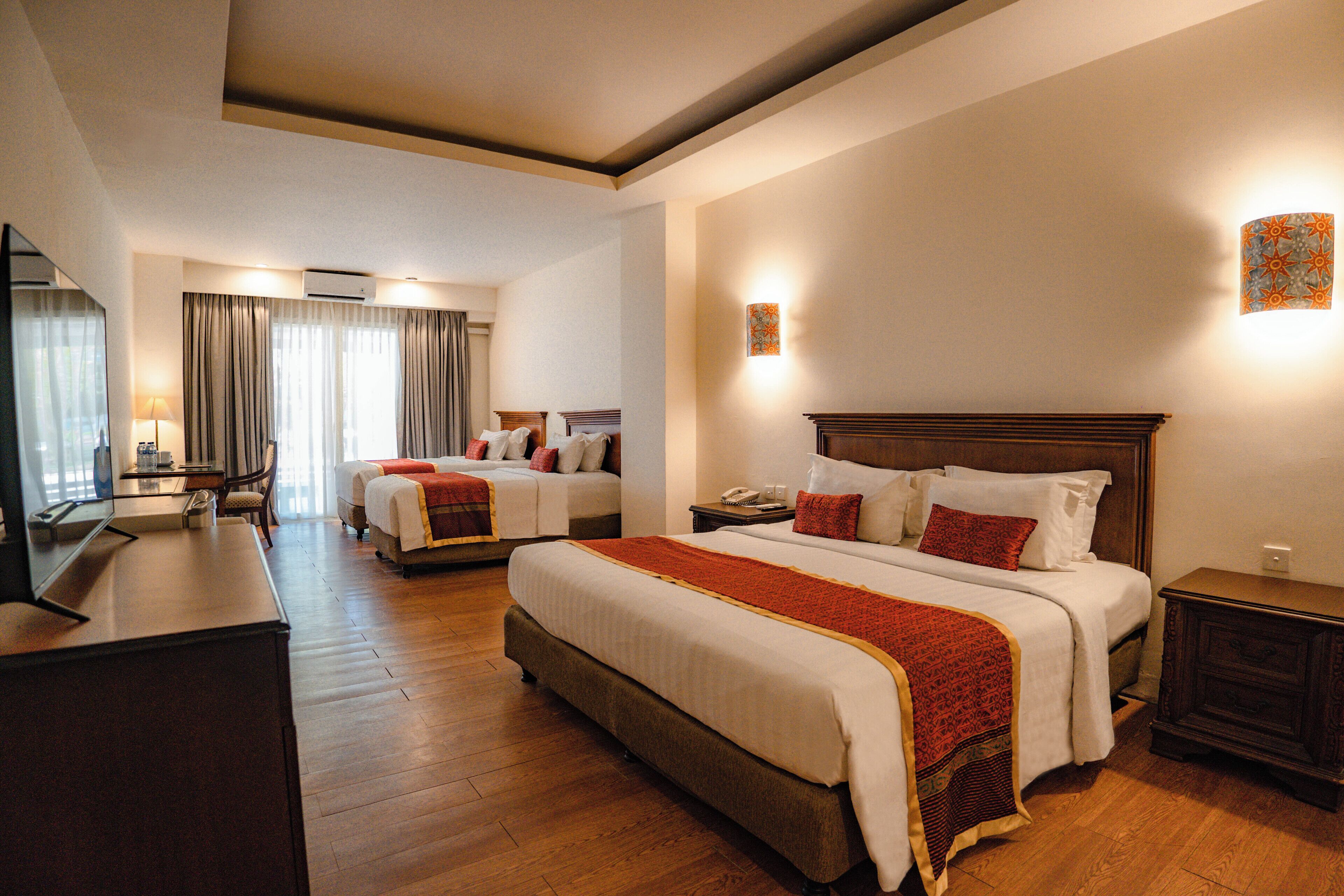 A hotel room with two beds, a desk, and a television.