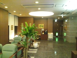 A lobby with a reception desk, seating area, and a large potted plant.
