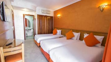 A hotel room with two beds, a TV, and a bathroom visible through an open door.