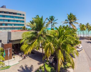 A hotel with a modern building, palm trees, and a view of the ocean. - Ritz Lagoa Da Anta (Maceió)