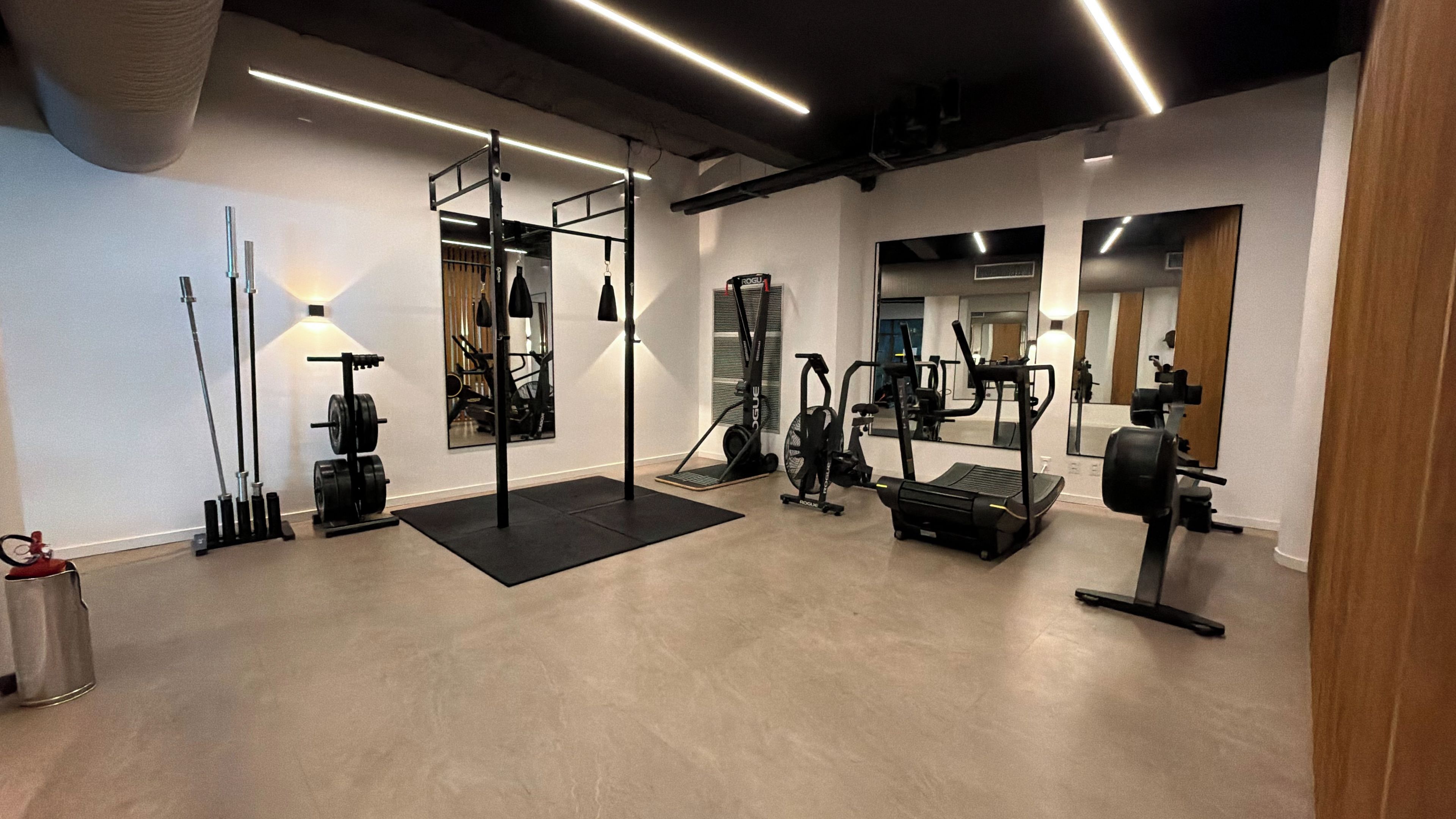 Un gimnasio con varios equipos de ejercicio, incluyendo una barra de dominadas, máquinas de pesas y una cinta de correr.