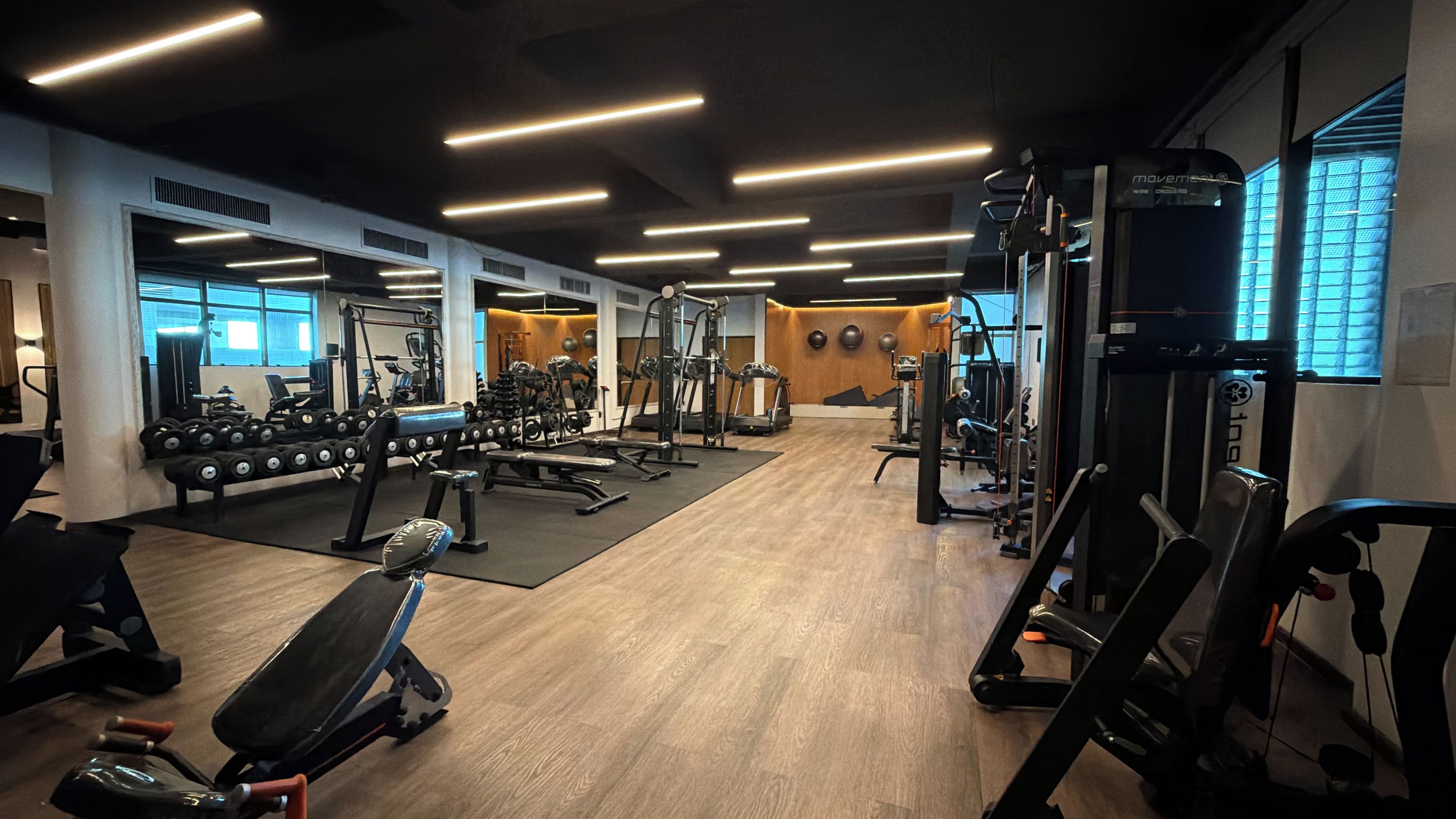 A gym with various exercise equipment, including dumbbells, benches, and weight machines.