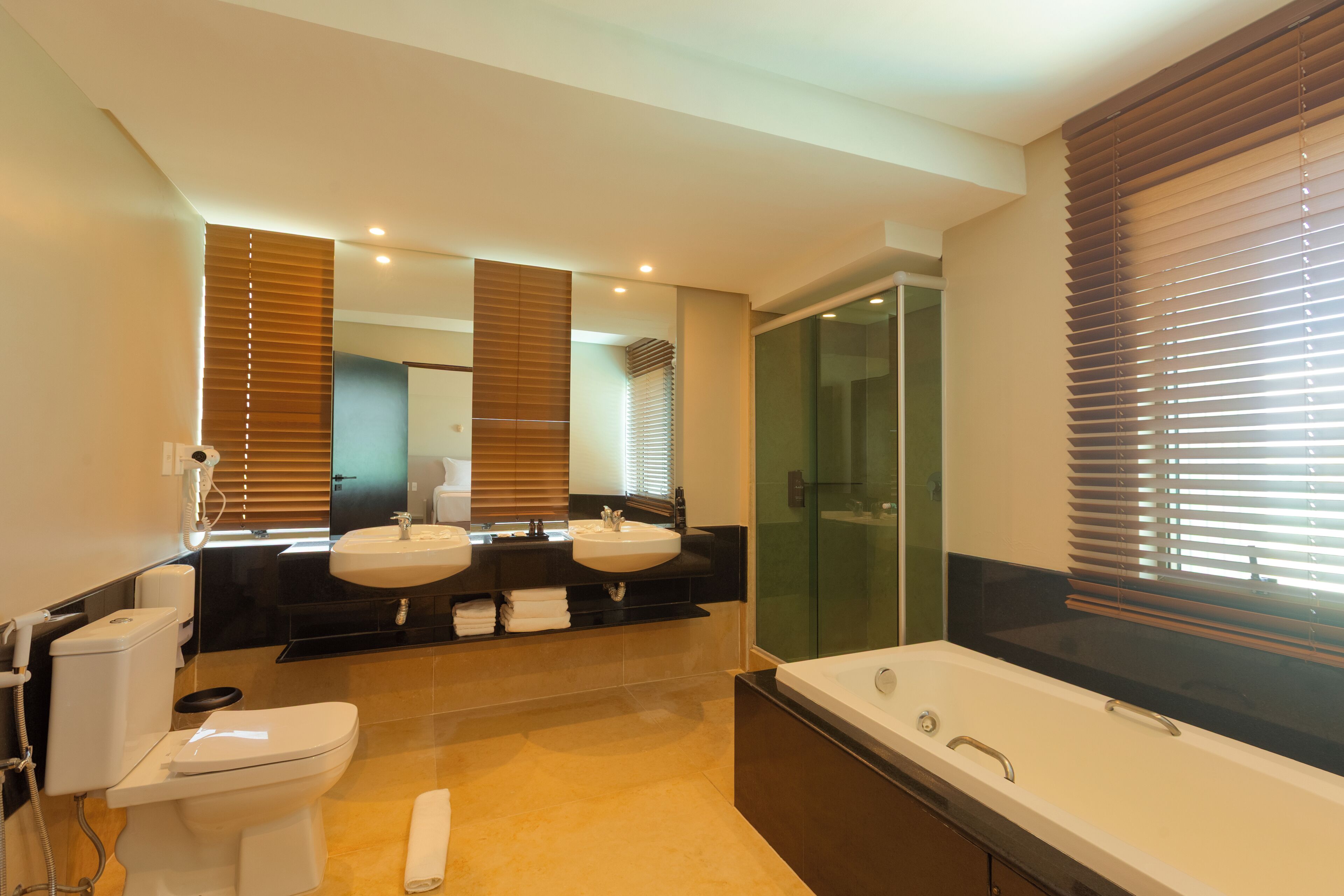 Ein modernes Badezimmer mit Toilette, zwei Waschbecken, einer Badewanne und einer Duschkabine aus Glas.