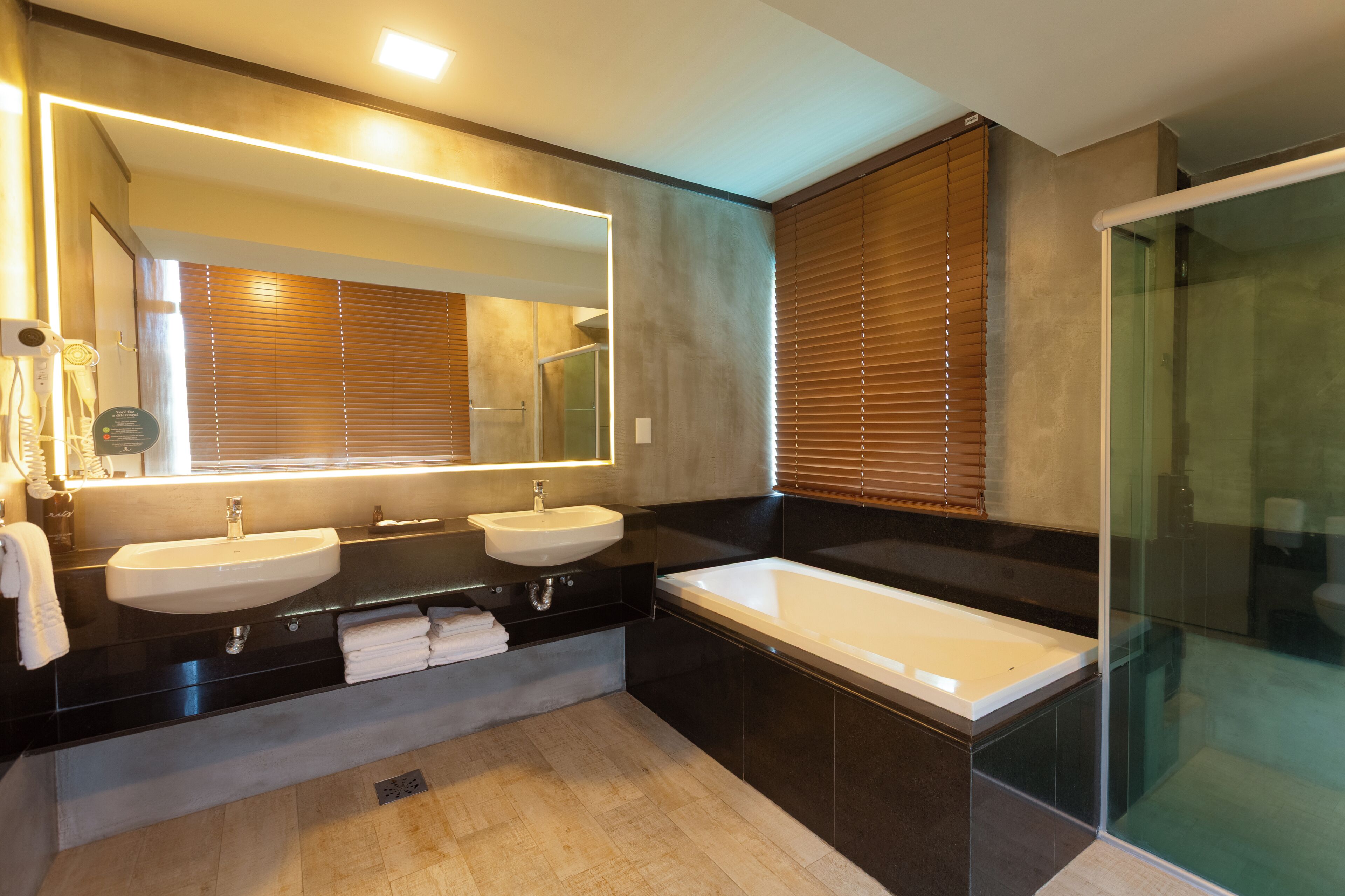 A modern bathroom with two sinks, a large bathtub, and a glass shower enclosure.