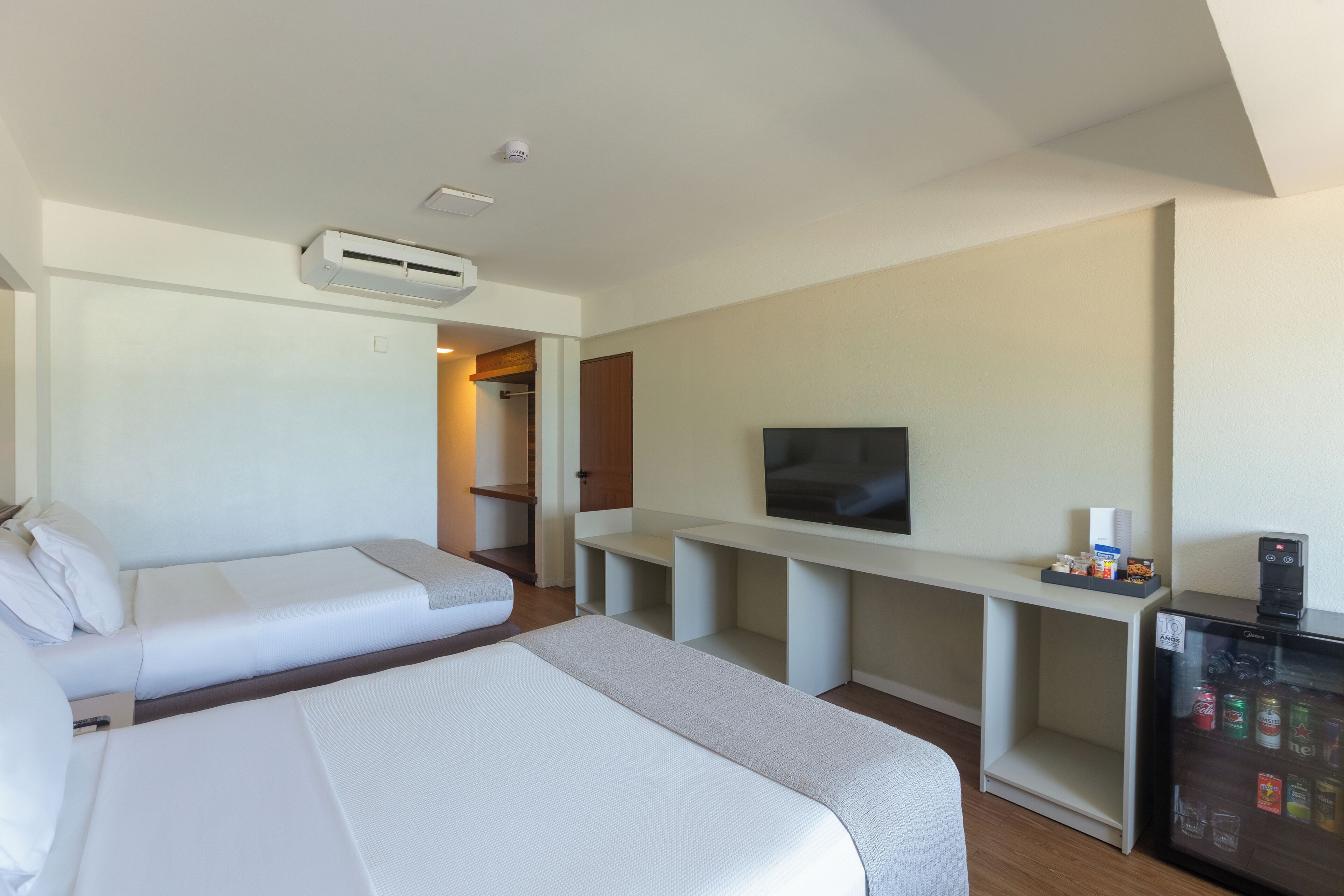 Habitación de hotel con cama, televisión, mini refrigerador y zona de estar.