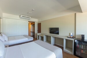 Habitación de hotel con cama, televisión, mini refrigerador y zona de estar.