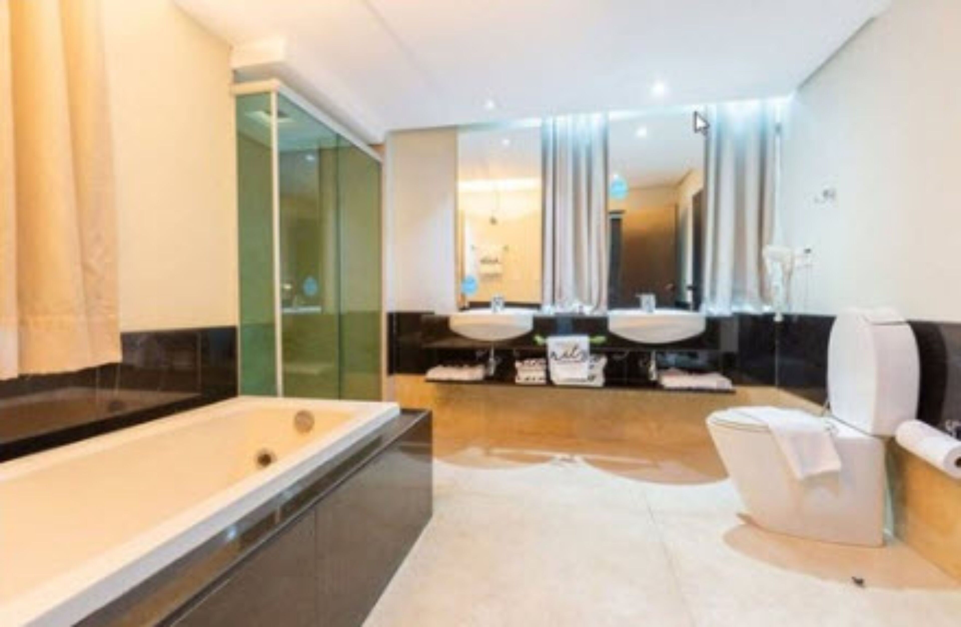Une salle de bain moderne dotée d’une grande baignoire, de deux lavabos et d’une douche à parois de verre.