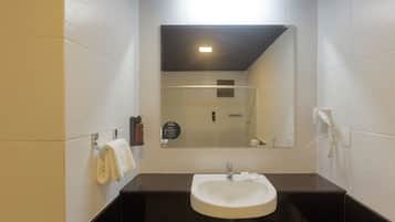 Un baño moderno con un lavamanos blanco, encimera oscura y un espejo sobre el lavamanos.