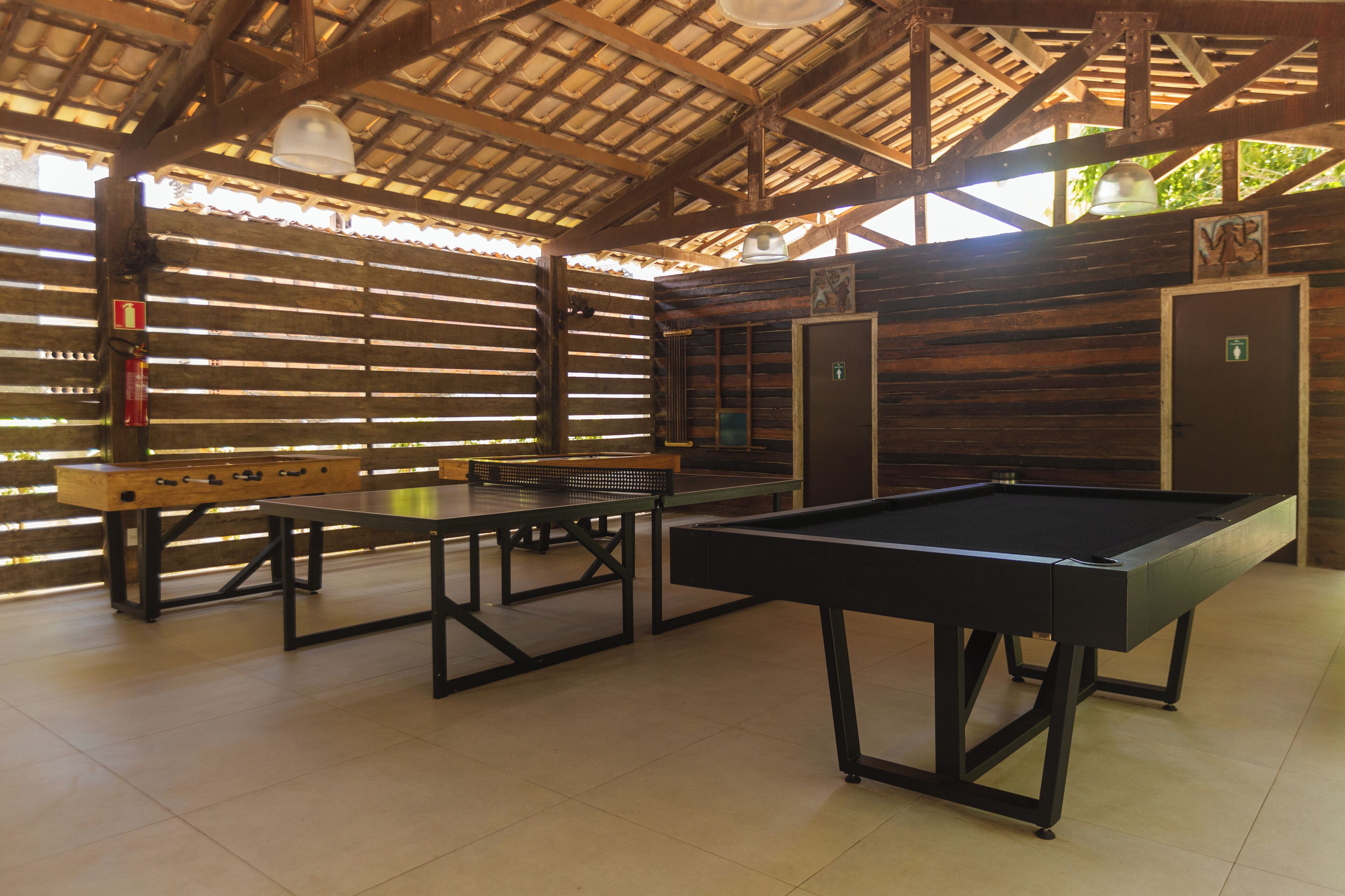 A recreational area with a pool table, ping pong table, and foosball table.