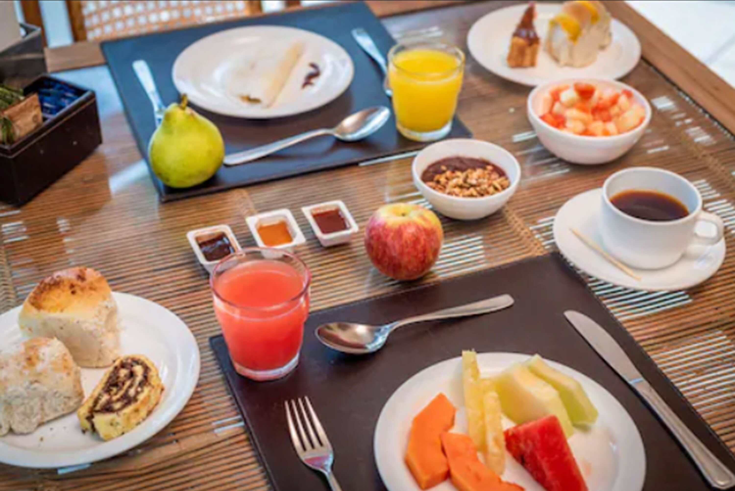 A breakfast setting with plates of food, a glass of orange juice, and a cup of coffee.