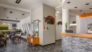 Et hotellets reception område med en marmorgulv, en receptionsdisk, et morgenmadsområde og en væghængt kunstværk.