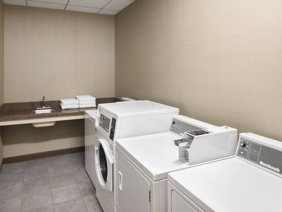 A laundry room with a washing machine, dryer, and a countertop with a sink and stacked towels.