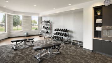 Ein modernes Fitnessstudio mit Krafttrainingsgeräten, Kurzhanteln und Bänken.