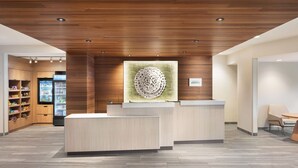 A modern reception area with wooden paneling, a central artwork, and a counter. - Fairfield Inn & Suites by Marriott West Kelowna (West Kelowna)