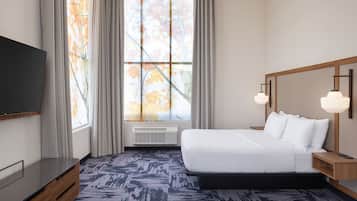Een moderne hotelkamer met een groot bed, een flatscreen televisie en een groot raam met gordijnen.