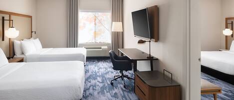 Une chambre d’hôtel avec deux lits, un bureau, une télévision et une fenêtre avec des rideaux.