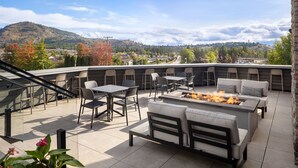A rooftop patio with outdoor seating, a fire pit, and a view of a hilly landscape. - Fairfield Inn & Suites by Marriott West Kelowna (West Kelowna)