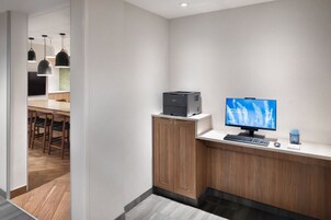 Una moderna zona de recepción con un escritorio de madera, un monitor de computadora e impresora.