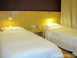 A hotel room with two single beds, a nightstand with a lamp, and a wall with a decorative pattern.
