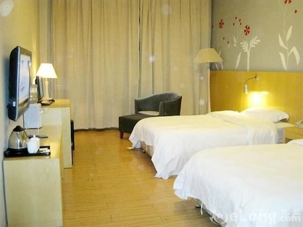 A hotel room with two beds, a desk with a lamp, a chair, and a TV.