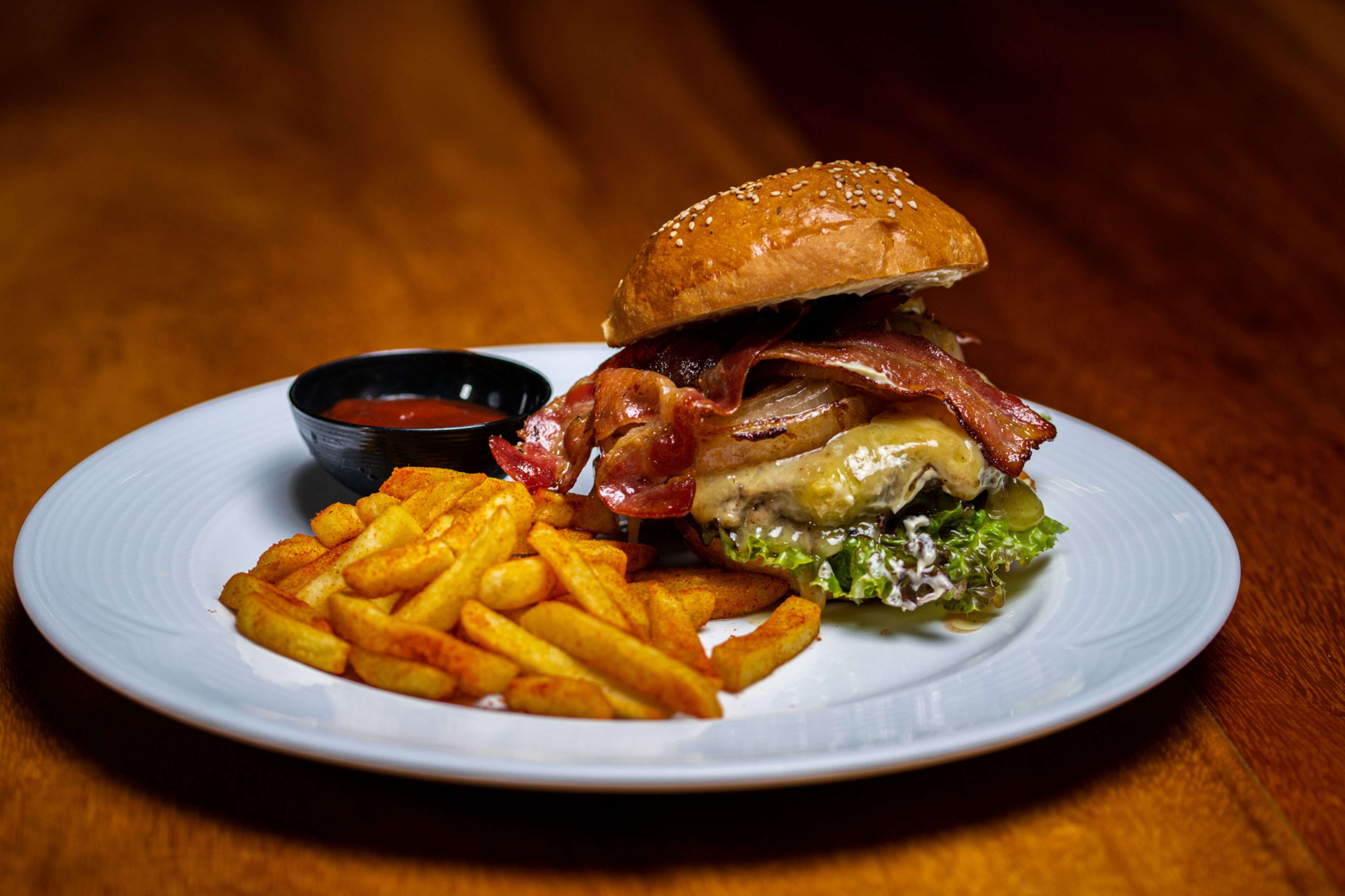 Un piatto con un hamburger, patatine fritte e una piccola ciotola di ketchup.