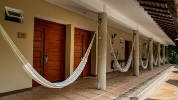 A hotel corridor with wooden doors, a hammock, and columns.