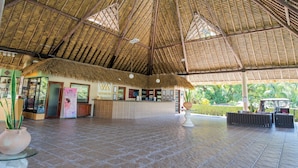 Un hall d’entrée spacieux avec un haut toit de chaume, un comptoir d’accueil et une enseigne indiquant «
VIVA Hotels
».