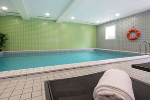 An indoor swimming pool with tiled walls, a lifebuoy, and a towel on a chair. - Nemea Appart Hotel Home Suite Nancy Centre (Nancy)