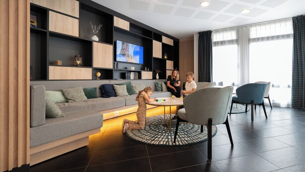 A modern living room with a sofa, a coffee table, and a TV mounted on a wall.