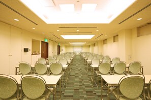 A conference room with rows of tables and chairs, a carpeted floor, and a ceiling with recessed lighting. - Smile Hotel Kumagaya (Kumagaya)