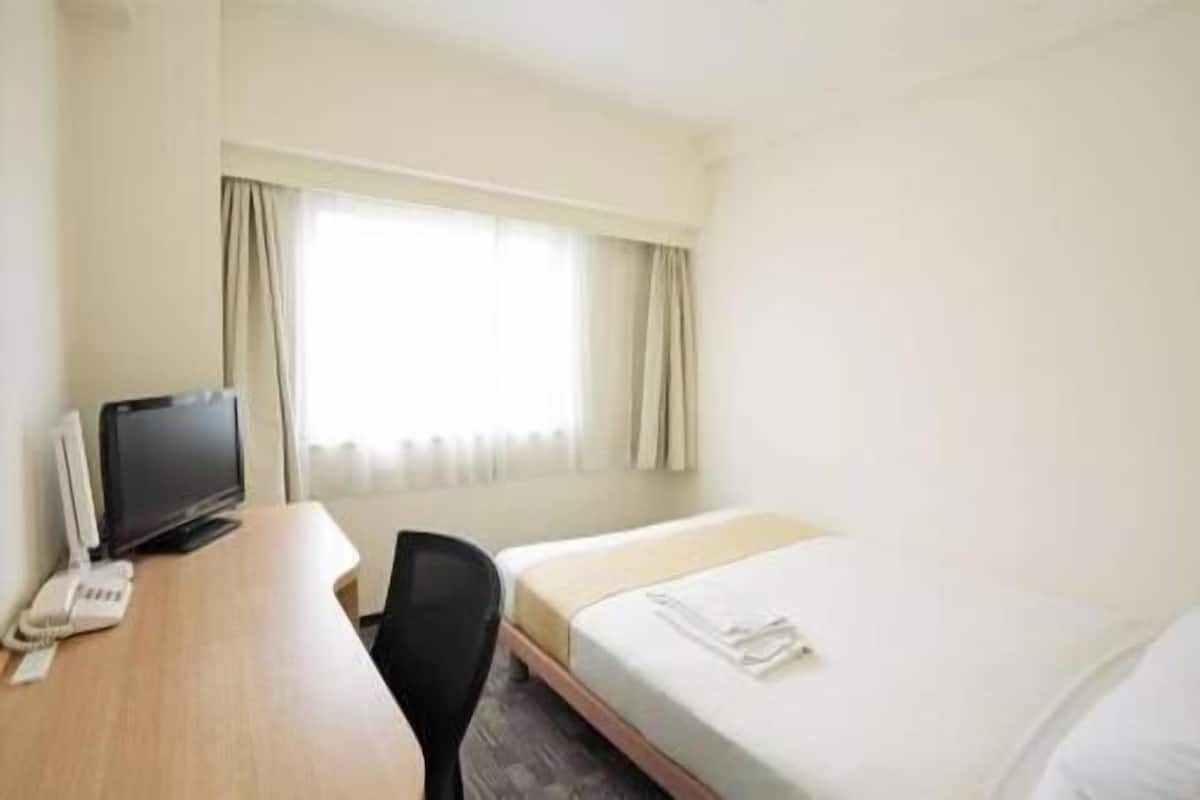Una habitación de hotel con una cama, un escritorio con computadora y una silla.