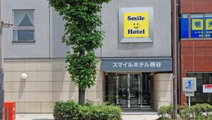 Entrada de un hotel con un letrero que dice "Smile Hotel" y otro letrero en un idioma extranjero.