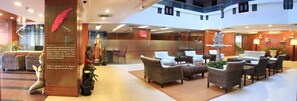 A spacious lobby with wicker furniture, a reception desk, and a statue.