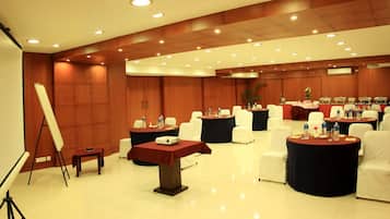 A conference room with round tables, white chairs, and a projector screen.