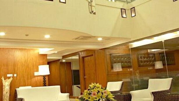 A multi-level hotel lobby with a curved staircase, seating areas, and a large mirror reflecting the space. - Shilton Royale (Bengaluru)