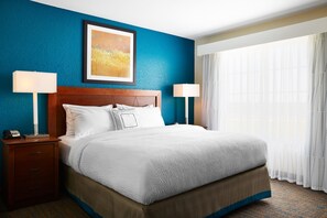 A hotel room with a large bed, two bedside tables with lamps, a framed artwork above the bed, and a large window with sheer curtains. - Residence Inn Norfolk Downtown (Norfolk)