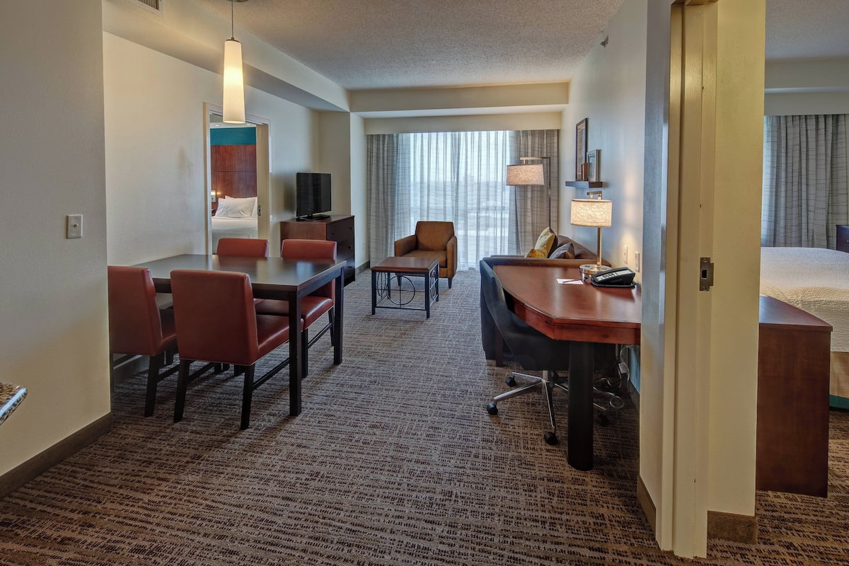A hotel room with a dining area, a sofa, a desk, and a bed.