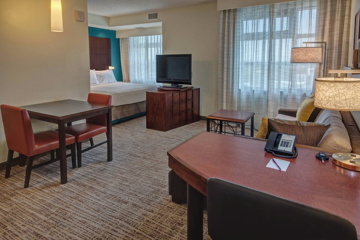 A hotel room with a bed, a TV, a desk with a phone, and a sofa.
