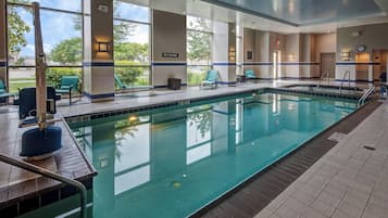 Une piscine à l’eau claire, entourée de chaises longues et d’un panneau indiquant « IL EST INTERDIT DE PLONGER ».