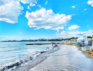 Une plage avec un ciel dégagé, une eau calme et une rangée de chaises de plage et de parasols.
